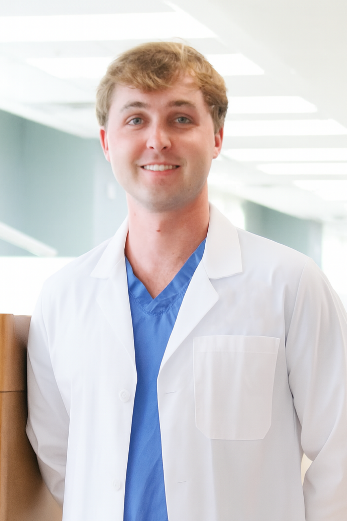 a male dentist in a white lab coat smiling